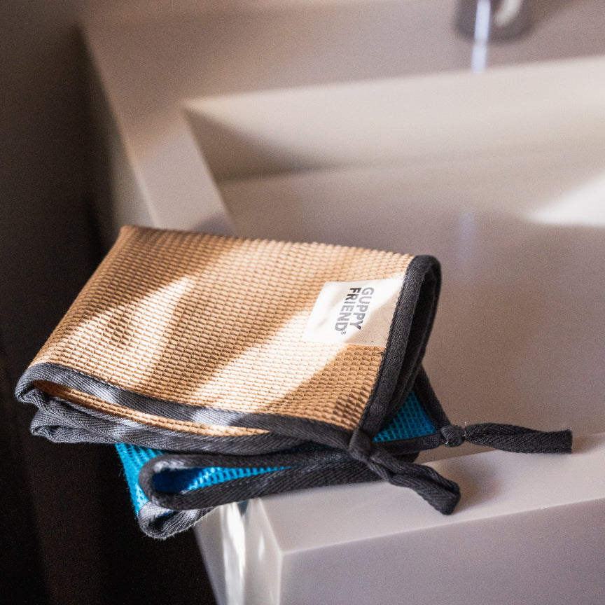 Guppyfriend Putztücher auf der Ecke eines Waschbeckens.