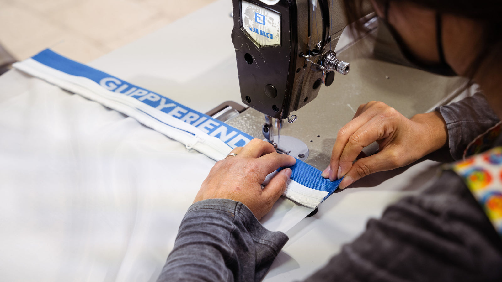 Eine Person näht das Guppyfriend Banner in den Waschbeutel ein.